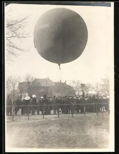 Fotografie Ballon, Gasballon / Fesselballon steigt vor einer Menschenmenge auf