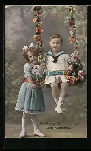 AK Junge und Mädchen sitzen auf Schaukel mit Blumen, Namenstag