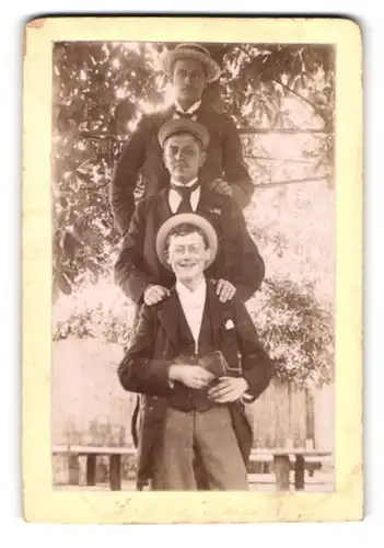Fotografie unbekannter Fotograf und Ort, drei lustige Studenten posieren übereinander für den Fotografen
