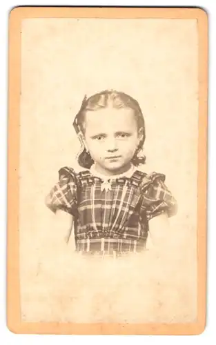 Fotografie unbekannter Fotograf und Ort, niedliches kleines Mädchen im karierten Kleid mit Haarschleife