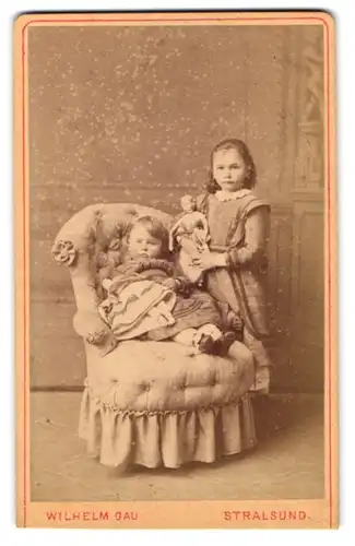 Fotografie Wilhelm Gau, Stralsund, zwei kleine Mädchen mit ihren Puppen im Atelier