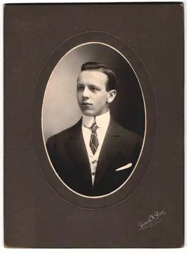 Fotografie Frank X. Pinz, Milwaukee / WI., junger Amerikaner im dunklen Anzug mit Fragezeichen Krawattennadel
