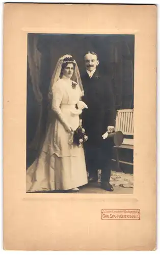 Fotografie Carl Spahn, Olbernhau i. S., junges Brautpaar im Hochzeitskleid und im Anzug mit Zylinder, Brautstrauss