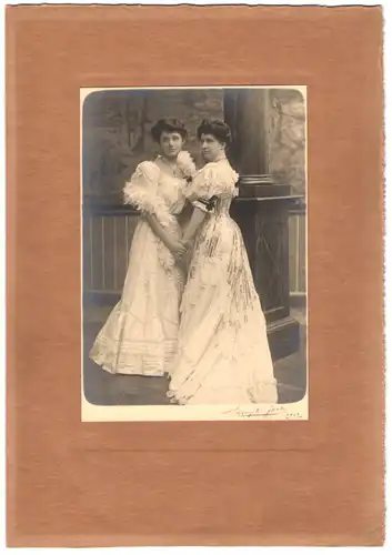 Fotografie Ferdinand Buyle, Brüssel, Portrait zwei hübsche junge Damen in schicken Kleidern halten Händchen, 18 x 26cm