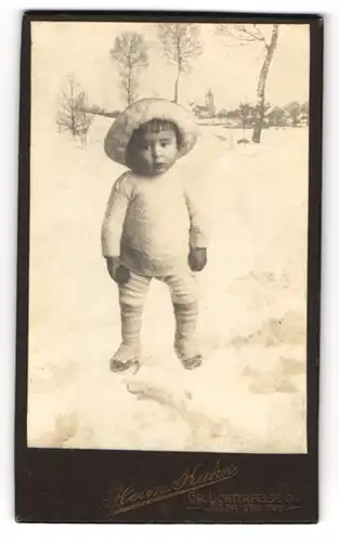 Fotografie Herrm. Kühn, Gross Lichterfelde, niedliches Kleinkind im Strampler steht in Winterlandschaft, Fotomontage