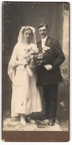 Fotografie Adolf Göldner, Arnau, Portrait junges Brautpaar im Hochzeitskleid und Anzug mit Melone und Brautstrauss