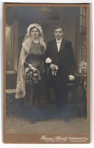 Fotografie Hermann Schmidt, Olbernhau i. Sa., junge Eheleute im schwarzen Brautkleid und im Anzug mit Zylinder