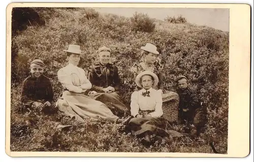 Fotografie unbekannter Fotograf und Ort, Grossmutter und Mutter mit ihren vier Kindern rasten auf einer Wiese im Sommer
