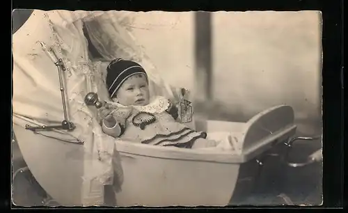 AK Baby mit Rassel im Kinderwagen