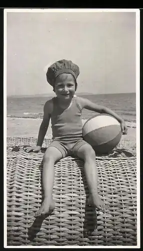 Fotografie niedliches Kind in Badebekleidung auf Strandkorb sitzend