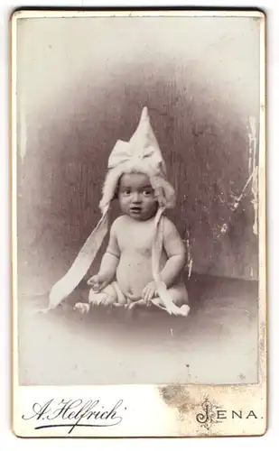 Fotografie A. Helfrich, Jena, niedliches Kleinkind mit Zipfelmütze und Bändern im Atelier
