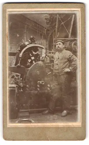 Fotografie unbekannter Fotograf und Ort, Fabrikarbeiter posiert an der Drehbank / Metallfräse