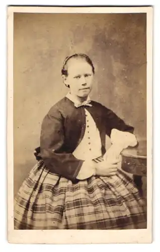 Fotografie H. Mencke, Itzehoe, junges Mädchen im karierten Rock mit Bluse und Haarreifen