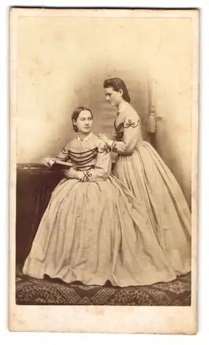 Fotografie unbekannter Fotograf und Ort, zwei hübsche junge Damen in karierten Kleidern posieren im Atelier