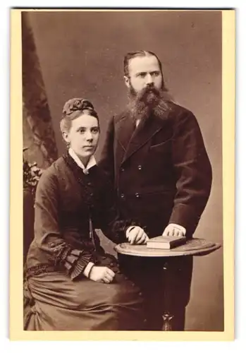 Fotografie Jean Baptiste Feilner, Bremen, Frau und Mann im dunklen Kleid und im Anzug mit Vollbart