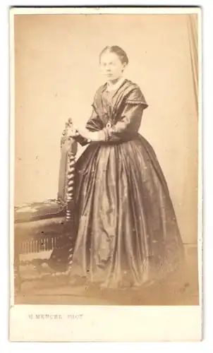 Fotografie H. Mencke, Hamburg, junge Dame im Kleid stehend am Stuhl