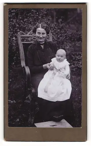 Fotografie unbekannter Fotograf und Ort, stolze Mutter präsentiert ihren Sohn Max im weissen Kleidchen