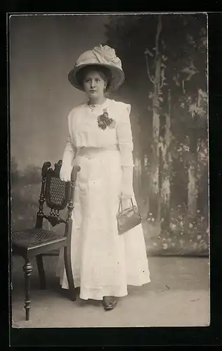 Foto-AK Dame im weissen Kleid mit schickem Hut, Studiokulisse