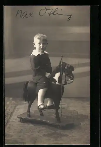 Foto-AK Niedlicher Junge sitzt auf Spielzeugpferd