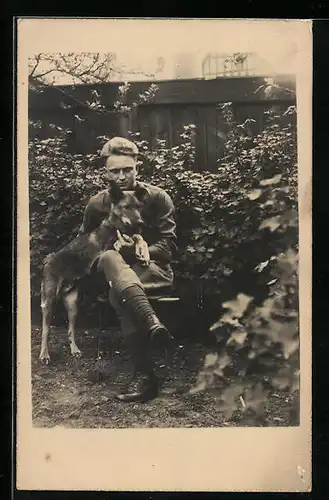 Foto-AK Junger Mann mit jungem Schäferhund in einem Garten