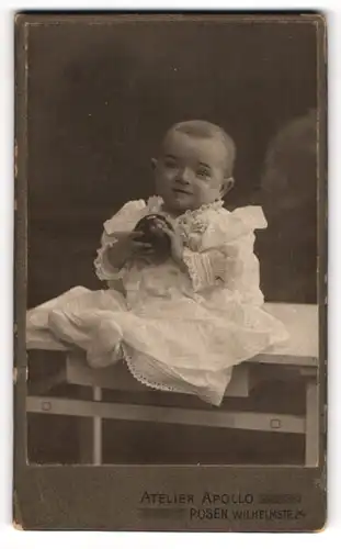 Fotografie Atelier Apollo, Posen, niedliches Kleinkind im weissen Kleidchen mit Ball in der Hand