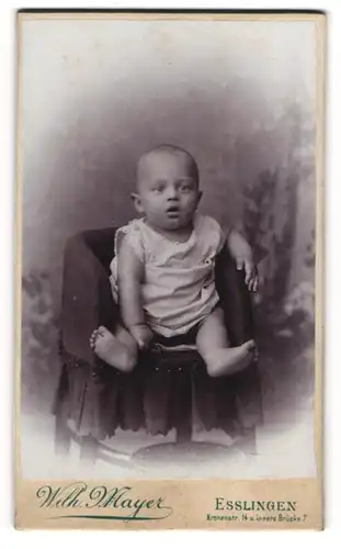 Fotografie Wilh. Mayer, Esslingen, Kleinkind im weissen Kleidchen sitzt im Kindersessel