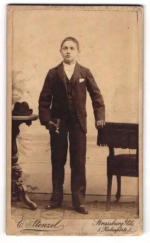 Fotografie C. Strenzel, Strassburg i. Els., junger Knabe im Anzug mit Hut auf dem Tisch