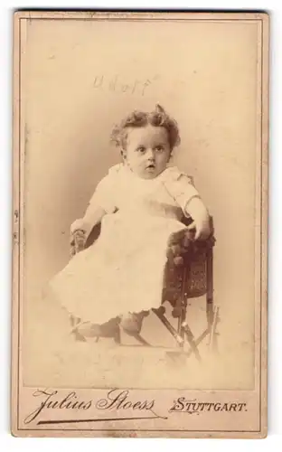 Fotografie Julius Stoess, Stuttgart, niedlicher Knabe Adolf im weissen Kleidchen auf Kinderstuhl