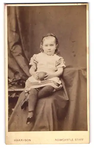 Fotografie Harrison, Newcastle-under-Lyme, niedliches englisches Mädchen im Kleid mit Ball in der Hand