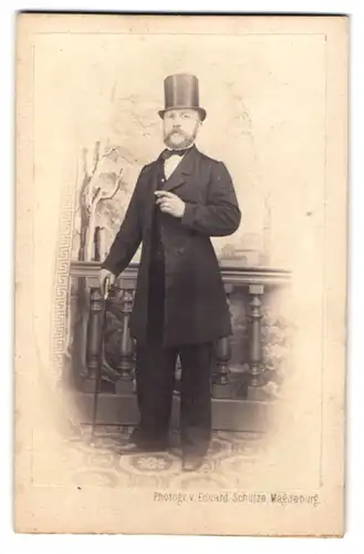 Fotografie Eduard Schütze, Magdeburg, Herr im Anzug mit Flanierstock und Zylinder