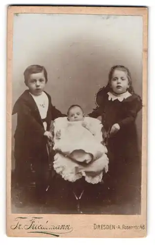 Fotografie Tr. Friedemann, Dresden-A., Rosenstr. 48, Zwei junge Kinder in bürgerlicher Kleidung mit Säugling auf Stuhl