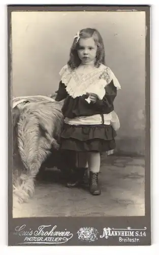 Fotografie Louis Frohwein, Mannheim, Breitestr., Süsses Mädel mit Schleife im schwarzen Kleid und Puppe in Hand