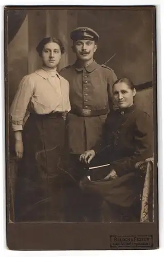 Fotografie Rausch & Pester, Karlsruhe, Erbprinzenstrasse 3, Junger Soldat in Feldgrau mit Mutter u. Schwester im Portrait