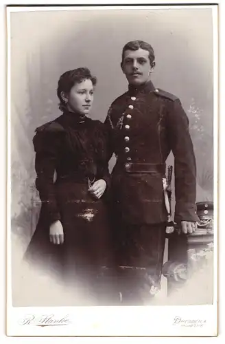 Fotografie R. Stanke, Dresden, Uhlandstrasse 6, Junger Soldat mit Schnauzer in Uniform mit Bajonett und seiner Frau