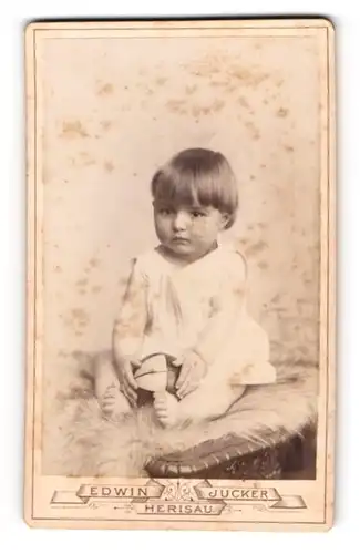 Fotografie Edwin Jucker, Herisau, Oberdorfstrasse 137, Süsses Kleinkind in weissem Kleidchen mit Ball in der Hand
