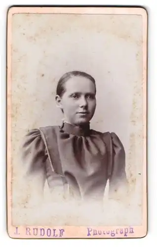 Fotografie J. Rudolf, Ort unbekannt, Hübsche junge Dame mit gebundenem Haar im bürgerlichen Kleid