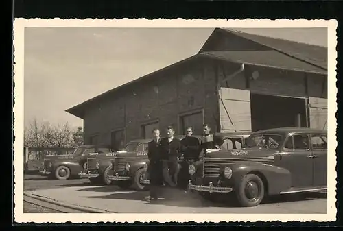 Foto-AK Autos vor einer Garage, daneben vier Herren 1950