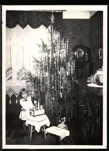 Fotografie Weihnachten, Mädchen spielt mit einer Kinderküche neben dem Weihnachtsbaum