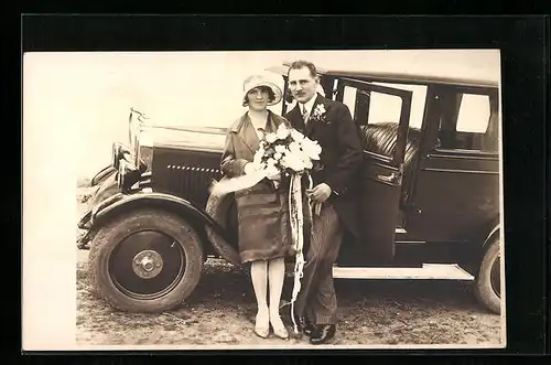 Foto-AK Auto auf einem Wiesenstück, daneben Hochzeitspaar 1929