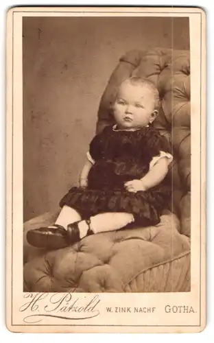 Fotografie H. Pätzold, Gotha, August-Strasse 7, Kleinkind im Kleidchen auf einem Sessel