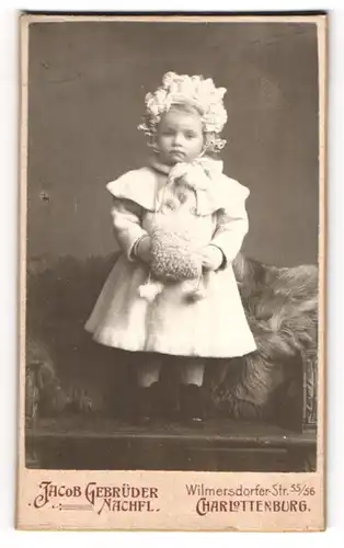 Fotografie Jacob Gebrüder Nachf., Berlin-Charlottenburg, niedliches Mädchen im Winterkleid mit Haube und Muff