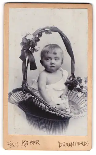 Fotografie Emil Kaiser, Düren / Rhld., Kleinkind sitzt in einem Weidenkorb mit Blumen