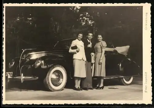 Foto-AK Auto am Strassenrand, davor zwei Damen und ein Herr