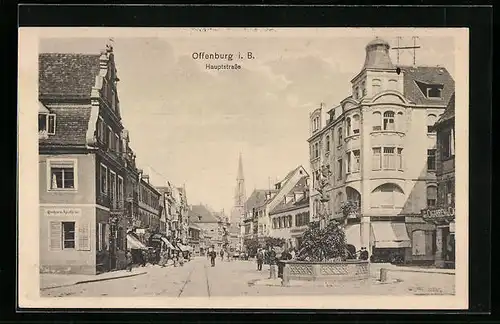 AK Offenburg i. B., Hauptstrasse mit Geschäften, Kirchturm und Brunnen