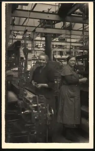 Fotografie Fabrikarbeiterinnen beim bestücken von Fertigungsmaschinen in einer Fabrik
