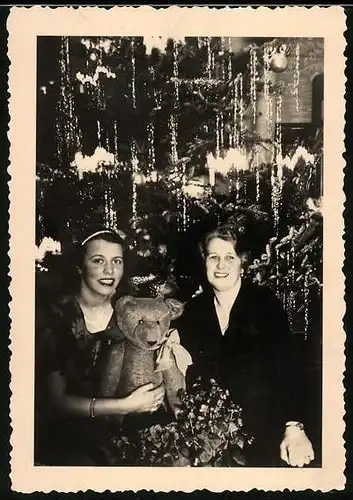 Fotografie Weihnachten, hübsche junge Frau mit Teddybär, Teddy vor dem Weihnachtsbaum