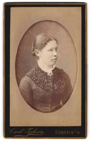 Fotografie Carl Tschira, Lörrach i/W., Junge bürgerliche Dame mit gebundenem Haar in schwarzem Kleid