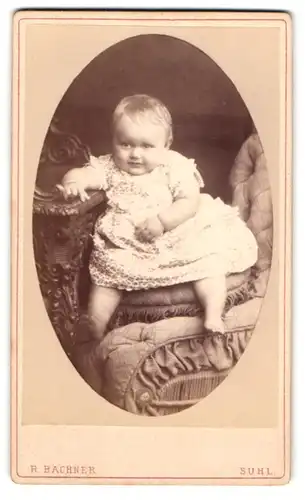 Fotografie R. Bachner, Suhl, Niedliches beleibtes Kleinkind in weissem Kleidchen auf einem Stuhl sitzend