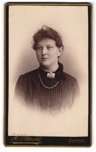 Fotografie H. Pätzold, Gotha, Gartenstrasse Nr. 50, Junge Dame mit gelocktem Haar in schwarzem Kleid mit Perlenkette