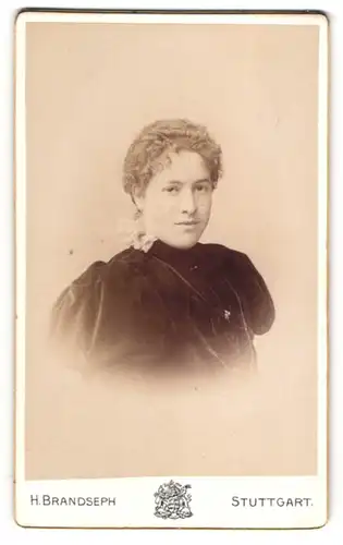 Fotografie H. Brandseph, Stuttgart, Marienstrasse 36, Hübsche Dame mit lockigem Haar im schwarzen Kleid mit Puffärmeln